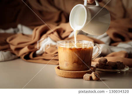 Pouring cream in black coffee. Pouring cream in black coffee. 130034320