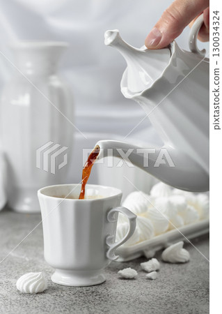 Black coffee in white porcelain cup and white small French meringues. 130034324