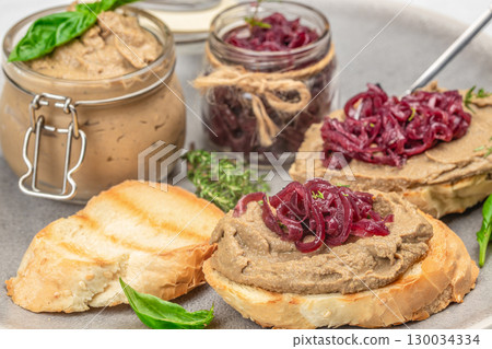 Toasted bread slices topped with liver pate and caramelized onions on a rustic plate Toasted bread slices topped with liver pate and caramelized onions on a rustic plate 130034334