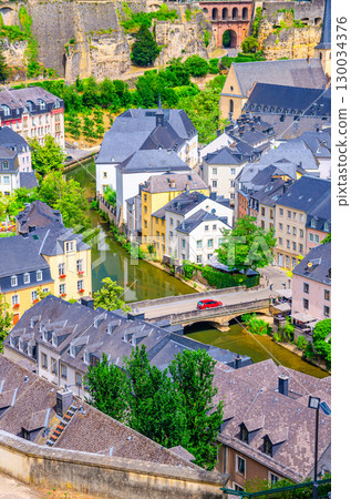 Luxembourg City historical centre aerial view with old colorful buildings on narrow streets, Pont du Grund bridge across Alzette river, top view of Luxembourg old town Grund district, vertical view Luxembourg City historical centre aerial view with old colorful buildings on narrow streets, Pont du Grund bridge across Alzette river, top view of Luxembourg old town Grund district, vertical view 130034376