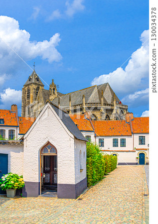 Beguinage Courtrai, Begijnhof van Kortrijk with white houses on narrow street in Kortrijk city historical centre and Church of Our Lady, vertical view, belgium landmark, Flemish Region, Belgium 130034378