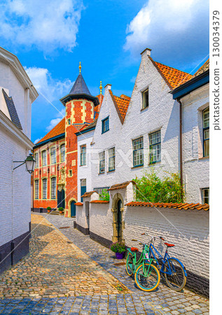 Beguinage Courtrai, Begijnhof van Kortrijk with white houses, bicycles near wall on narrow paving stone street in Kortrijk city historical centre, vertical view, belgium landmark, Belgium 130034379