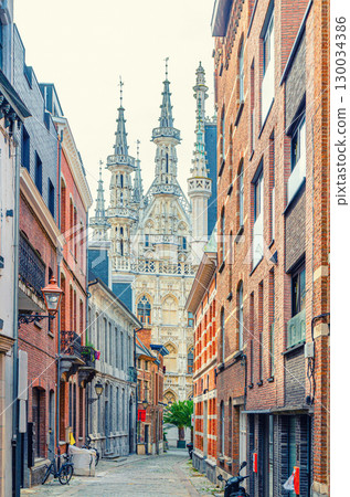 Vertical view of narrow pedestrian street of old town Leuven historical city center with Town Hall Historisch Stadhuis van Leuven Brabantine Gothic style building background, Flemish Region, Belgium 130034386