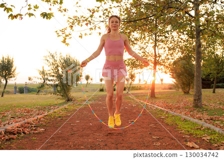 Fit sportswoman jump rope outdoors in autumn park 130034742