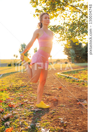 Fit sportswoman does the stretching outdoors in autumn park Fit sportswoman does the stretching outdoors in autumn park 130034748
