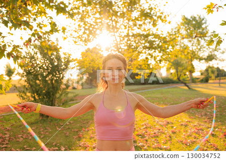 Fit sportswoman jump rope outdoors in autumn park 130034752