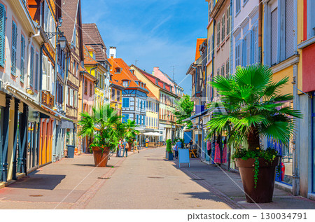 Pedestrian street Rue Vauban with old colorful houses medieval buildings with color walls and shutters windows, palms in pots in old town Colmar city historic centre, Alsace Grand Est region, France 130034791