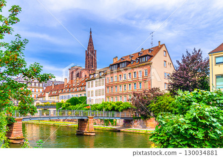 Old medieval buildings on quay embankment, pasarelle pedestrian bridge across River Ill canal and Strasbourg Cathedral background in old town Strasbourg city historic Centre, Alsace region, France 130034881
