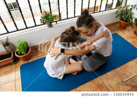 Mother and Daughter Practicing Yoga on a Sunny Balcony Terrace 130034954