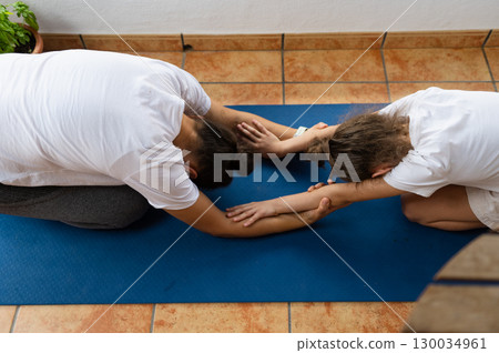 Mother and Daughter Practicing Yoga Together on a Blue Mat 130034961