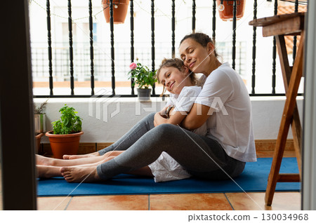 Mother and Daughter Sharing a Loving Moment on a Cozy Balcony Mother and Daughter Sharing a Loving Moment on a Cozy Balcony 130034968