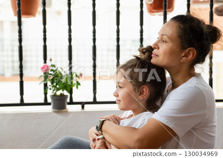 Mother and Daughter Embracing on a Balcony with a Potted Flower Mother and Daughter Embracing on a Balcony with a Potted Flower 130034969