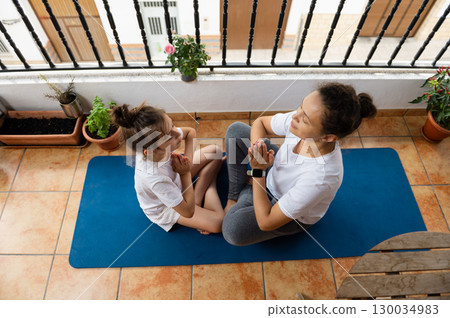 Mother and Daughter Practicing Yoga Together on an Outdoor Patio Mother and Daughter Practicing Yoga Together on an Outdoor Patio 130034983