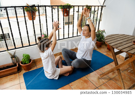Mother and Daughter Practicing Yoga on a Balcony Together 130034985