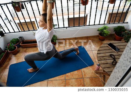 Woman Practicing Yoga on Balcony in a Tranquil Outdoor Setting 130035035