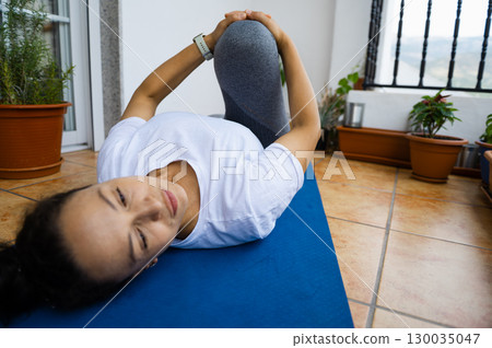 Woman Practicing Relaxation and Stretching Poses on a Balcony Yoga Mat Woman Practicing Relaxation and Stretching Poses on a Balcony Yoga Mat 130035047