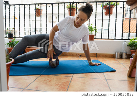 Woman Practicing Yoga With Foam Roller on a Balcony 130035052
