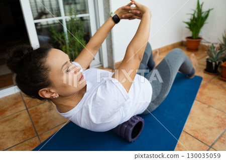 Woman Practicing Foam Rolling Exercises on Mat At Home Woman Practicing Foam Rolling Exercises on Mat At Home 130035059