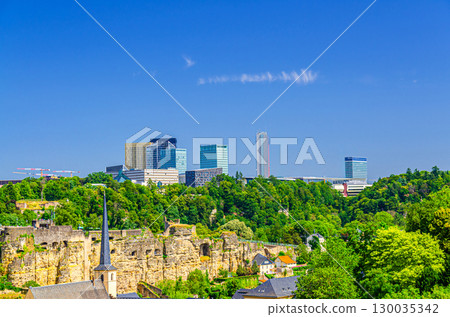 Luxembourg City aerial panoramic view of Kirchberg central business district with skyscraper buildings and Three Acorns Park with green trees, Luxembourg cityscape skyline horizon with blue sky Luxembourg City aerial panoramic view of Kirchberg central business district with skyscraper buildings and Three Acorns Park with green trees, Luxembourg cityscape skyline horizon with blue sky 130035342