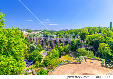 Pulvermuhl Viaduct Biisser Breck railway stone arch viaduct bridge across Alzette valley and Maierchen stone defensive wall in Luxembourg City historical centre, park with green trees and blue sky Pulvermuhl Viaduct Biisser Breck railway stone arch viaduct bridge across Alzette valley and Maierchen stone defensive wall in Luxembourg City historical centre, park with green trees and blue sky 130035343