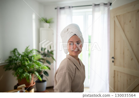 young woman enjoying hair care routine in cozy bathroom. 130035564