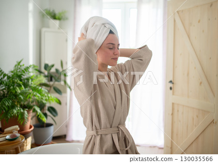 young woman enjoying hair care routine in cozy bathroom. 130035566