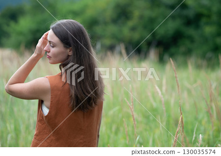 Woman connecting with nature during calming countryside stroll. Woman connecting with nature during calming countryside stroll. 130035574