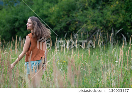 Woman connecting with nature during calming countryside stroll. Woman connecting with nature during calming countryside stroll. 130035577