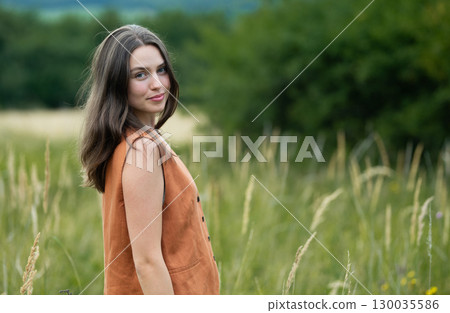 Natural beauty of young woman in orange dress in the middle of meadow. 130035586