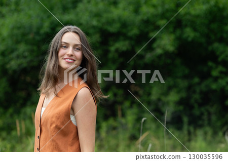 Portrait of young woman smiling outdoors in summer nature. 130035596