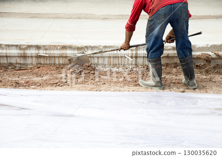 Workers are using shovels to level the ground before pouring concrete at a road construction site. Workers are using shovels to level the ground before pouring concrete at a road construction site. 130035620