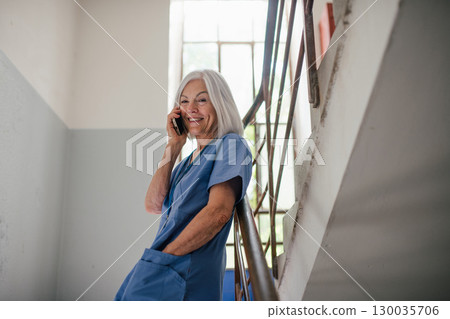 Mature nurse taking break during hospital shift, making phone call. 130035706