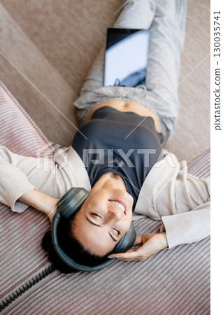 Woman relaxing at home, enjoying music after work. Woman relaxing at home, enjoying music after work. 130035741