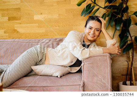 Relaxed woman taking a break, resting on sofa. 130035744