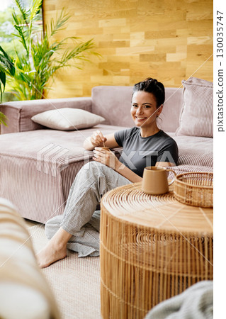 Relaxed woman taking a break, sitting on carpet and drinking coffee. Relaxed woman taking a break, sitting on carpet and drinking coffee. 130035747