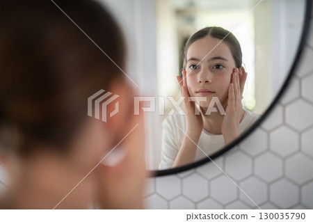 Teenager treating acne, taking care of her skin at home. 130035790