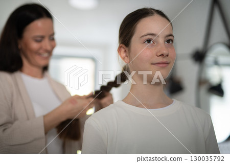 Mother braiding daughters thick hair in bathroom. Mother braiding daughters thick hair in bathroom. 130035792