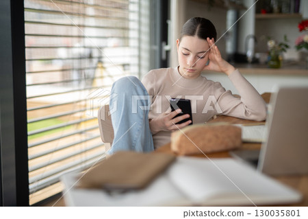 Stressed teenager checking her phone 130035801