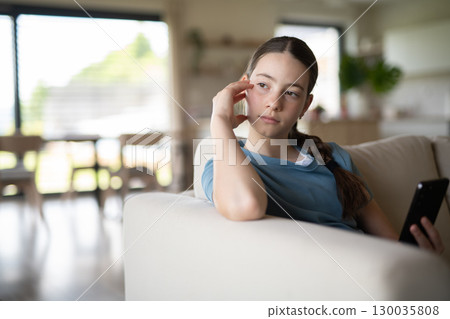 Teen girl looking at phone with worried expression. 130035808