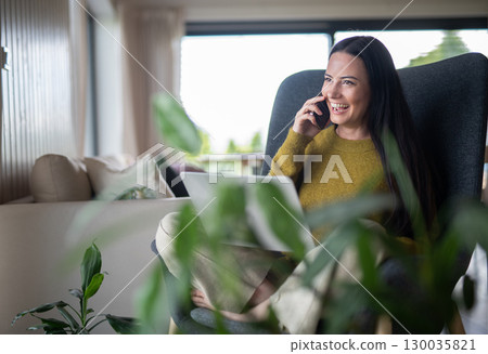 Female freelancer working from home, making phone call with client. Female freelancer working from home, making phone call with client. 130035821