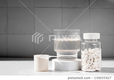 Food supplement concept. Capsules of probiotics, vitamins, white pills and a scoop of protein collagen powder.  130035927
