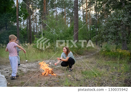 Family Roasting Marshmallows Over Campfire in Forest Family Roasting Marshmallows Over Campfire in Forest 130035942