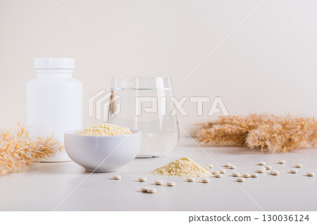 Peptide powder in a bowl and a glass of water on the table Peptide powder in a bowl and a glass of water on the table 130036124