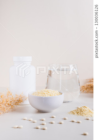 Peptide powder in a bowl and a glass of water on the table vertical view Peptide powder in a bowl and a glass of water on the table vertical view 130036126