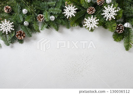 Christmas frame with evergreen branches and carving wooden eco natural decorations, snowflakes, pine cones on white background. Copy space. Xmas greeting card. Winter Holiday. View from above. Christmas frame with evergreen branches and carving wooden eco natural decorations, snowflakes, pine cones on white background. Copy space. Xmas greeting card. Winter Holiday. View from above. 130036512