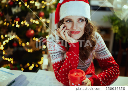 pensive business woman in green office with Christmas tree 130036858