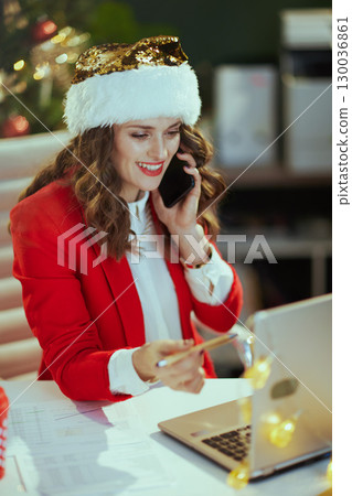 smiling talking on phone in green office with Christmas tree smiling talking on phone in green office with Christmas tree 130036861