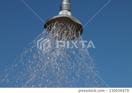 Shower head pouring water against blue sky on sunny day Shower head pouring water against blue sky on sunny day 130036879