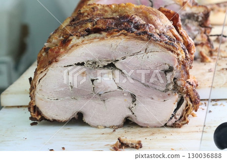 Delicious porchetta resting on cutting board showing its seasoning 130036888