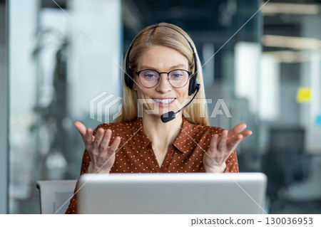 Confident businesswoman with glasses and headset participates in a video call, exemplifying remote collaboration and effective communication within a professional work environment. 130036953